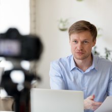 Mann i blå skjorte ser inn i kamera
